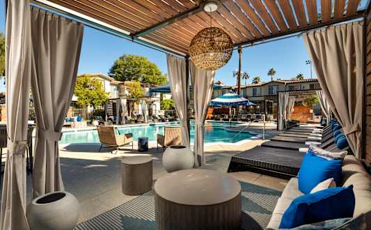 A poolside lounge area with blue cushions and a woven basket hanging from the ceiling.