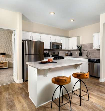A kitchen with white cabinets and a wooden floor.
