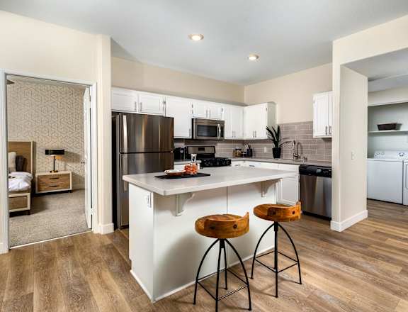 A kitchen with white cabinets and a wooden floor.