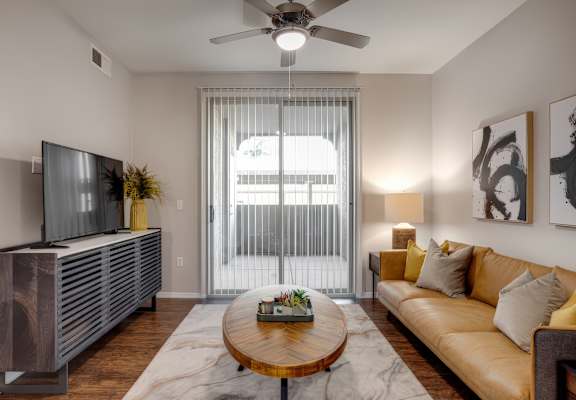 A living room with a brown couch, a wooden coffee table, and a flat-screen TV.