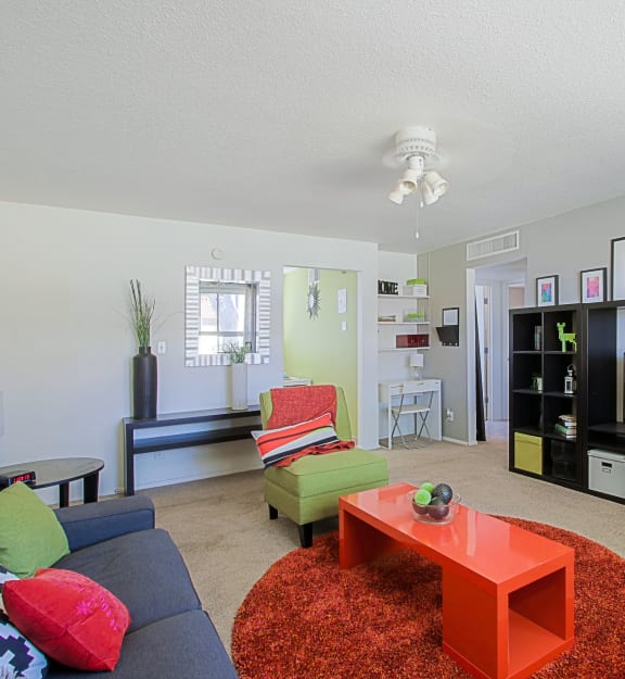 a living room with a blue couch and green chair and a red coffee table