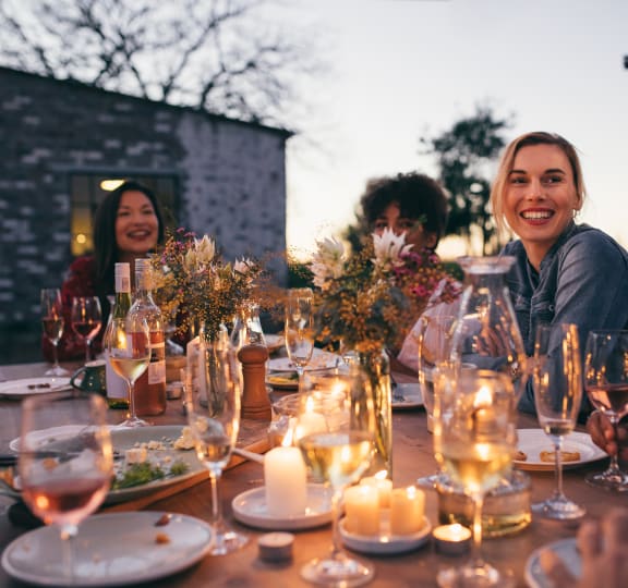 A group of people enjoying a meal and drinks at a candlelit table at The Rey Downtown, Phoenix, 85003