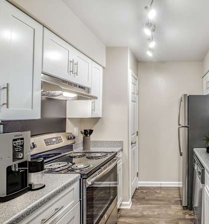 A kitchen with a stove, refrigerator, and sink.