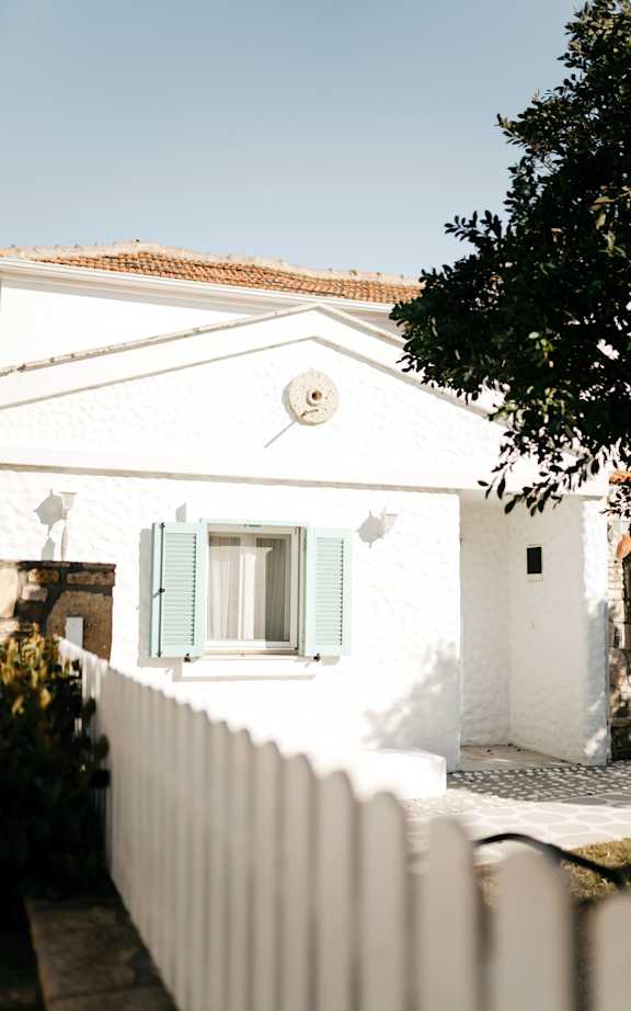 A white house with green shutters and a white picket fence.