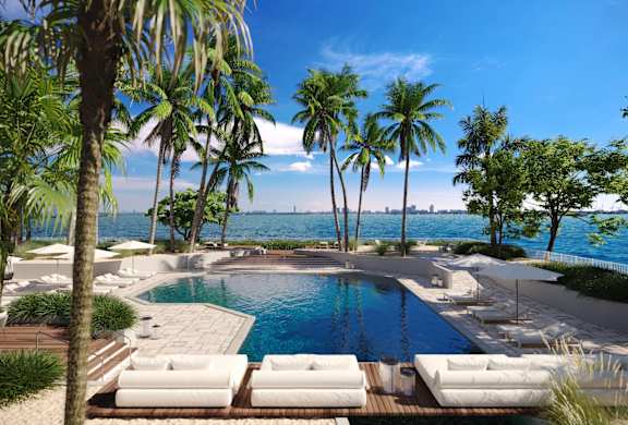 a swimming pool with palm trees and a body of water at The Hamilton, Miami, Florida
