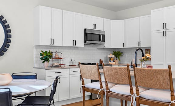 A kitchen with white cabinets and a round mirror on the wall.