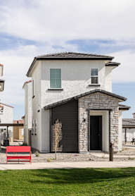 A white house with a black door and a red bench in front.