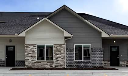 A two-story house with a stone facade and black doors.