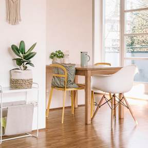 A chair with a pillow and a blanket is in front of a bookshelf.