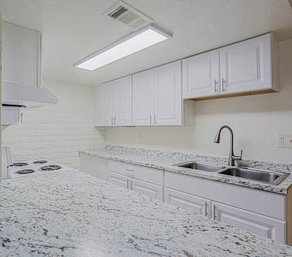 A kitchen with a marble countertop and white cabinets.