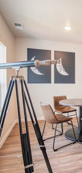 A room with a table and chairs and a tripod with a camera on it.