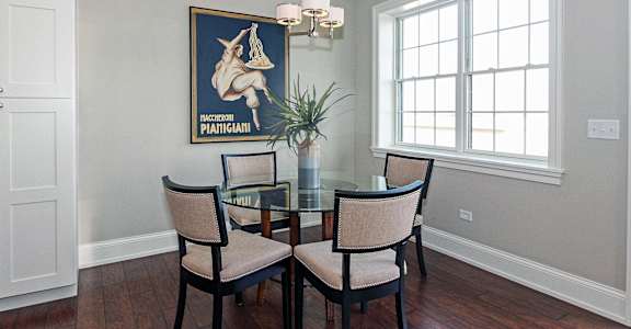 a dining room with a table and chairs and a painting on the wall