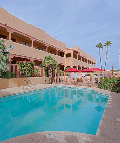 A pool in front of a building with a palm tree.