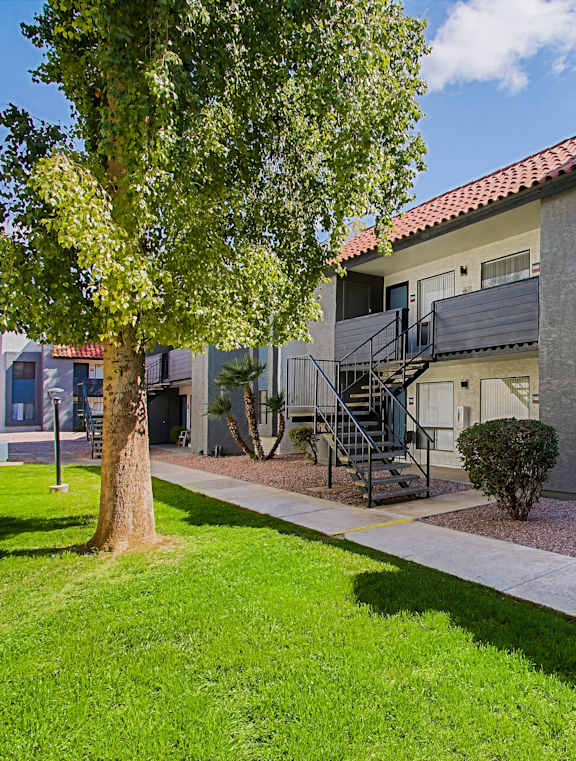 A tree is in front of a building with a red tile roof.