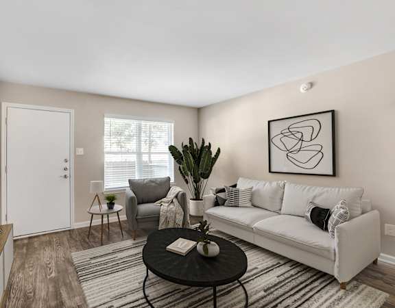 A living room with a white couch, a black coffee table, and a large painting on the wall.