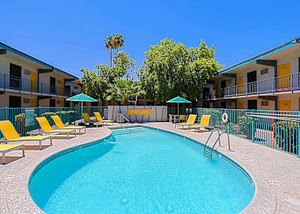 A swimming pool surrounded by yellow sun loungers and green umbrellas.