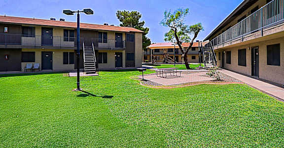 A grassy courtyard with a lamp post and a tree in front of apartment buildings.