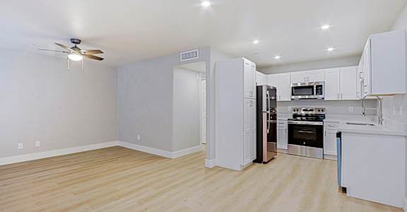 A kitchen with white cabinets and appliances in a room with a ceiling fan.