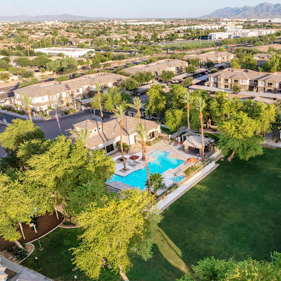 A bird's eye view of a neighborhood with a swimming pool and green lawns.