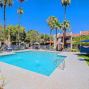 A large swimming pool surrounded by a fence and trees.