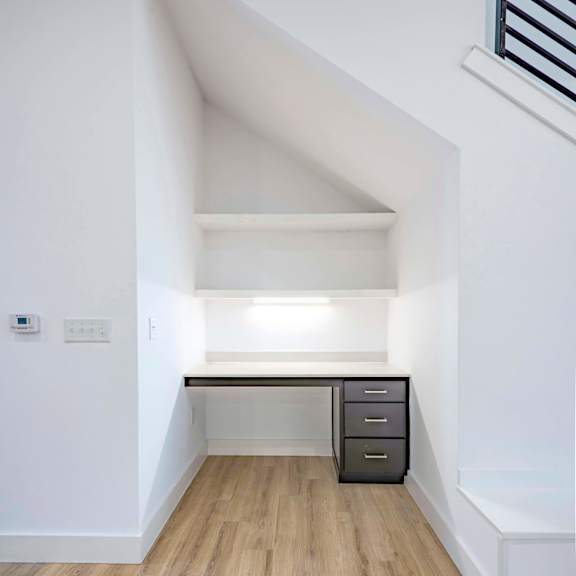 A white room with a desk and drawers.