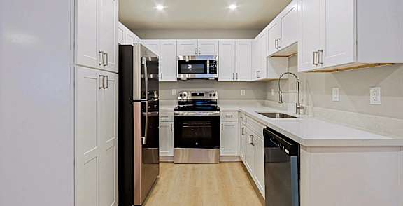 a large white kitchen with stainless steel appliances and white cabinets