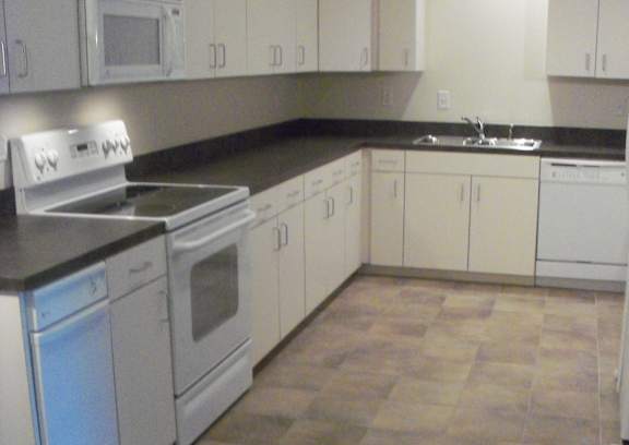 A kitchen with white cabinets and a black counter top.