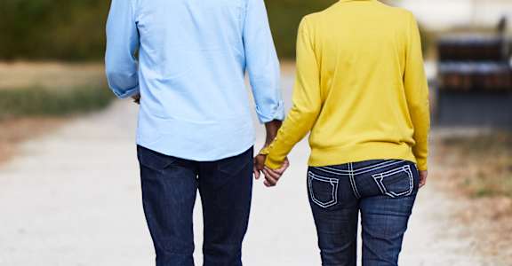 an older couple walking down a path holding hands