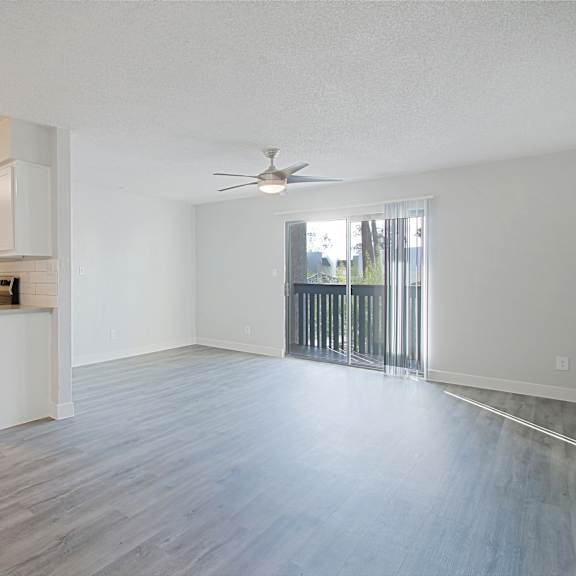 A spacious kitchen with white cabinets and a wooden floor.