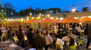 A group of people are gathered at an outdoor evening event.