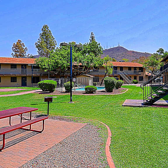 A red picnic table is in the middle of a grassy courtyard.