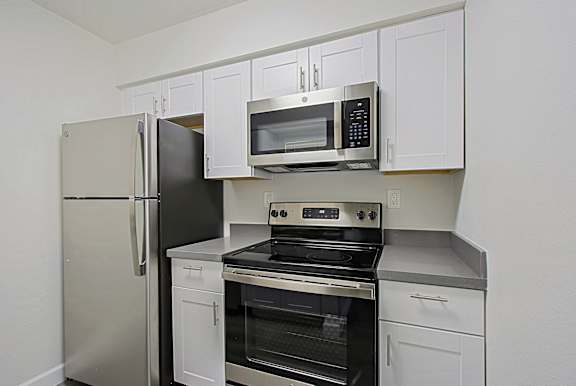 A kitchen with a stainless steel refrigerator, oven, and microwave.