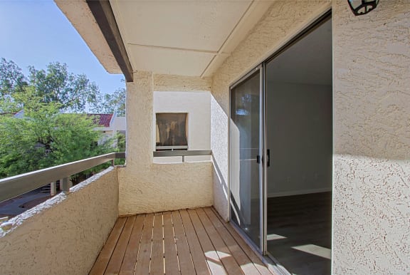 a balcony with a sliding glass door and a wood deck