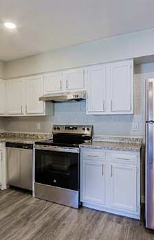 A kitchen with white cabinets and a stainless steel refrigerator.