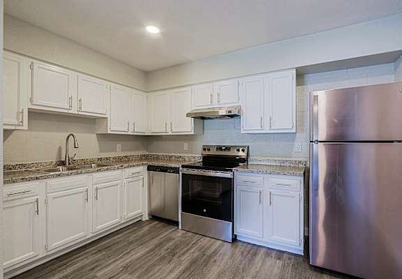 A kitchen with white cabinets and a stainless steel refrigerator.