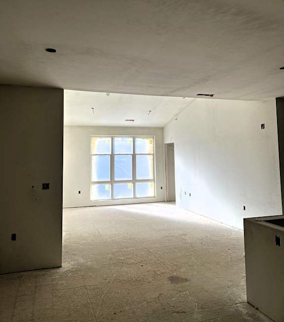 A large empty room with a window and a door.