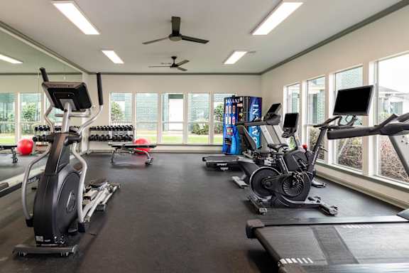 A gym with treadmills, elliptical machines, and a fan.