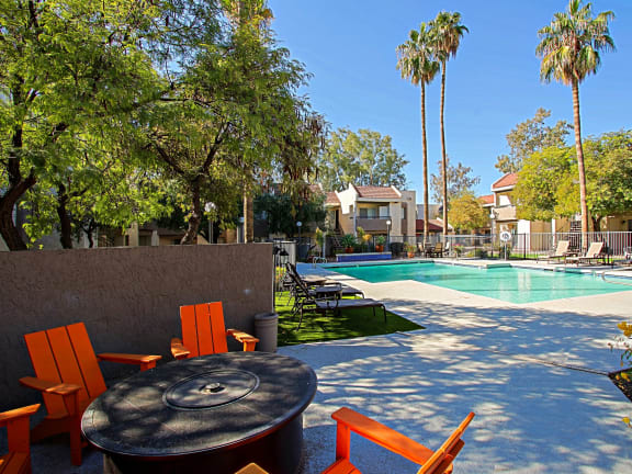 a backyard with a pool and orange chairs and a table