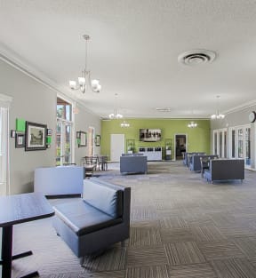 a resident clubhouse with couches tables and chairs and a large screen tv