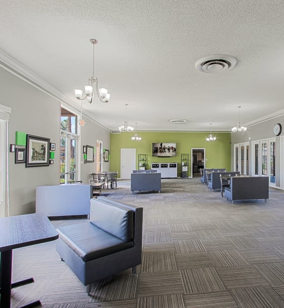 a resident clubhouse with couches tables and chairs and a large screen tv