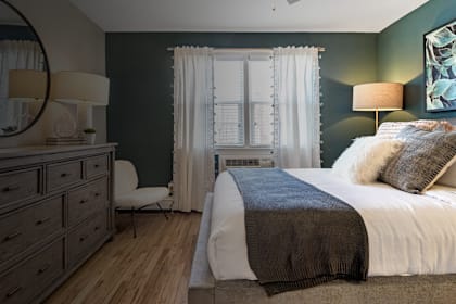 A bedroom with a bed, nightstand, and chair. at Alister Morristown, Morristown, NJ, 07960
