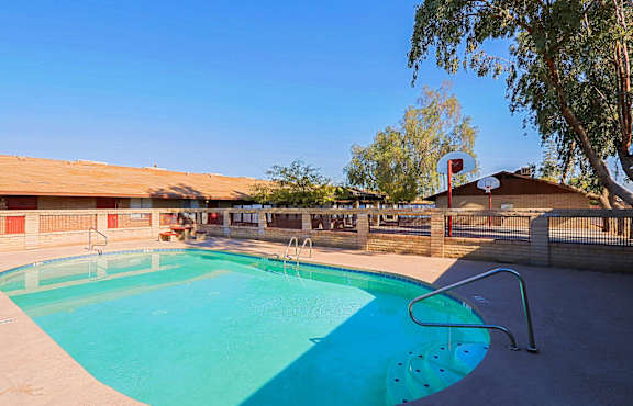 A swimming pool with a basketball hoop in the background.