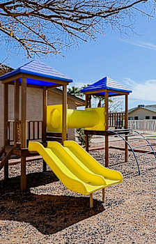 A playground with a yellow slide and a blue roofed structure.