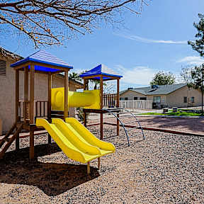 A playground with a yellow slide and a blue roofed structure.