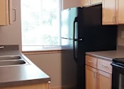 Thumbnail 3 of 5 - a kitchen with a black refrigerator freezer next to a window