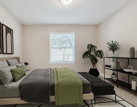 A bedroom with a bed, a green blanket, and a potted plant.