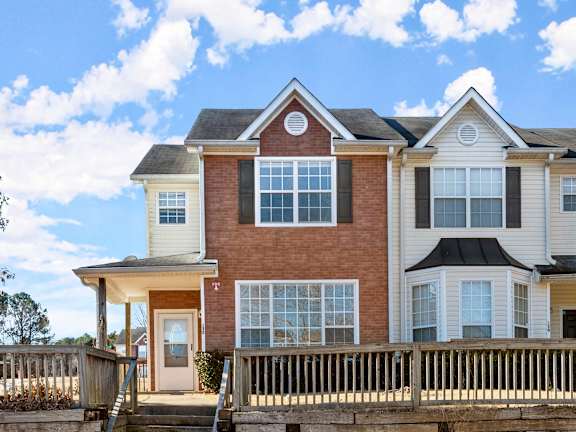 A two-story house with a brown brick exterior and white trim.