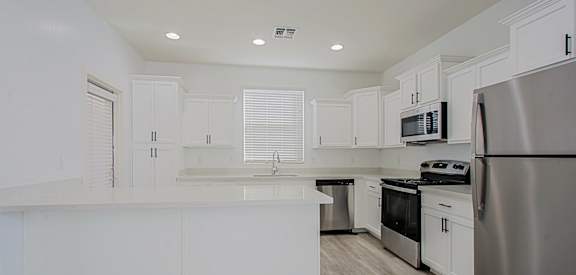 an empty kitchen with white cabinets and stainless steel appliances