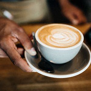 a person holding a cup of coffee on a plate