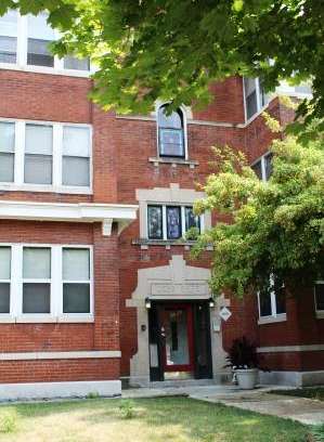 A red brick building with a black door and a small porch.